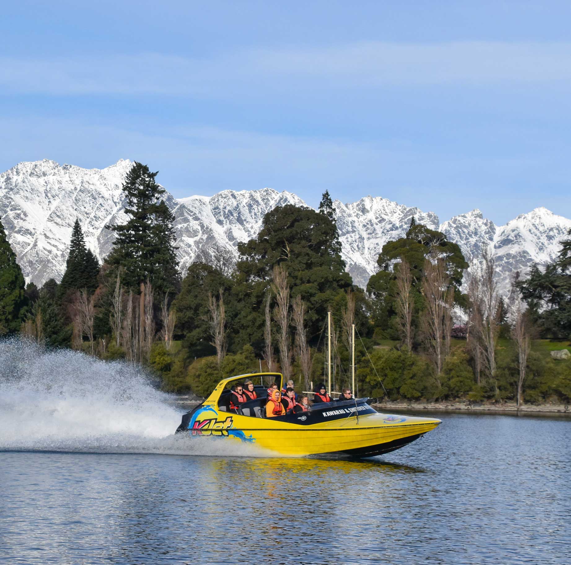 KJet jet boating in winter on lake Wakatipu with lots of snow on the Remarkables mountain range next to Queenstown gardens